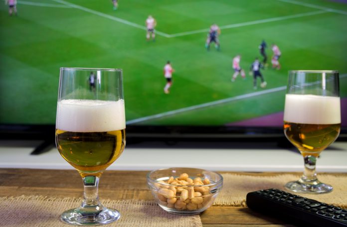 Glasses of beer and football match in background Glasses of beer and football match in background