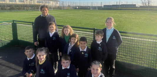 Johnny Mercer MP pictured in front of the 3G pitch with youngsters at Marine Academy Plymouth
