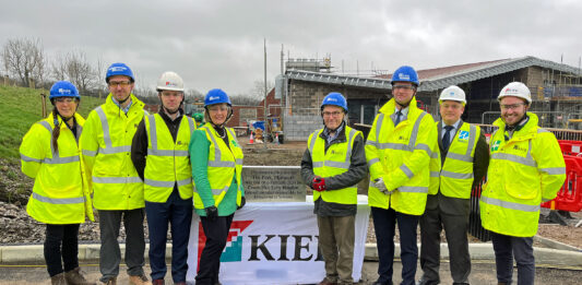 People in high vis clothing stand outside a building site