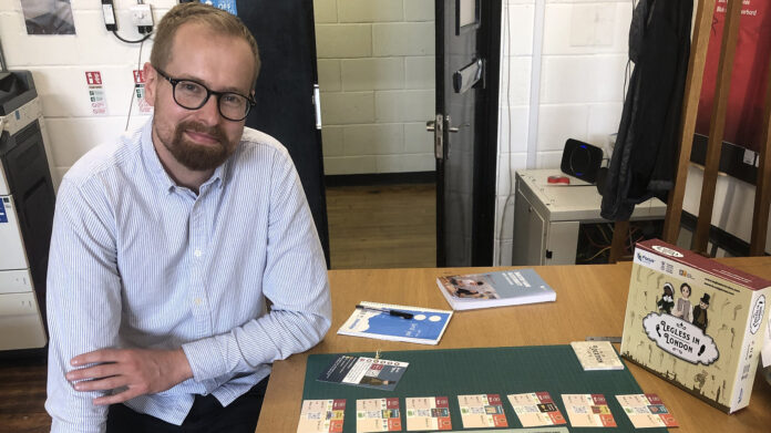 Dr Ryan Sweet with a copy of the board game Legless in London, which was inspired by his research (Credit - Focus Games)